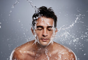 A young man splashing water on his face